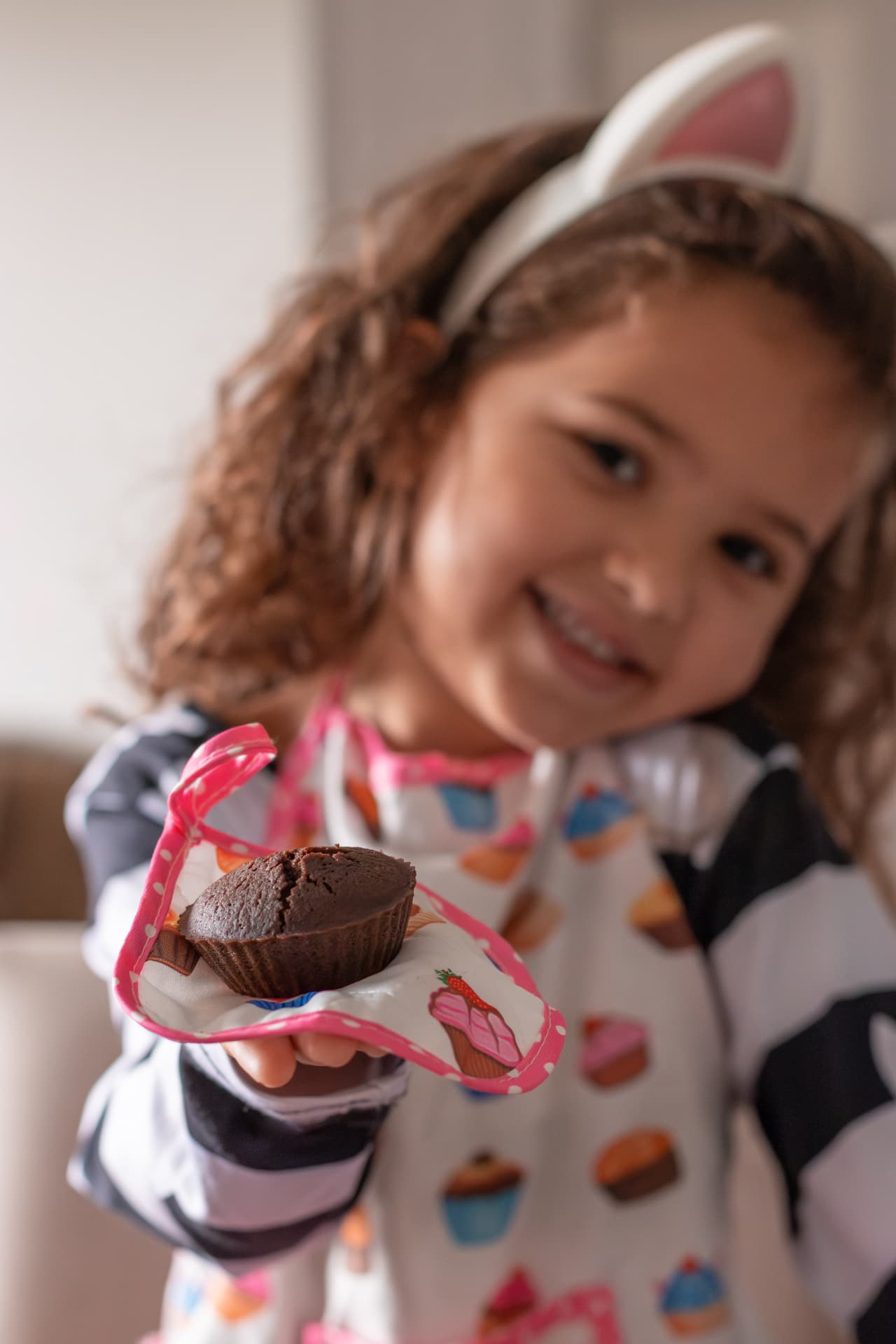 Criança sorrindo segurando um bolinho na lancheira